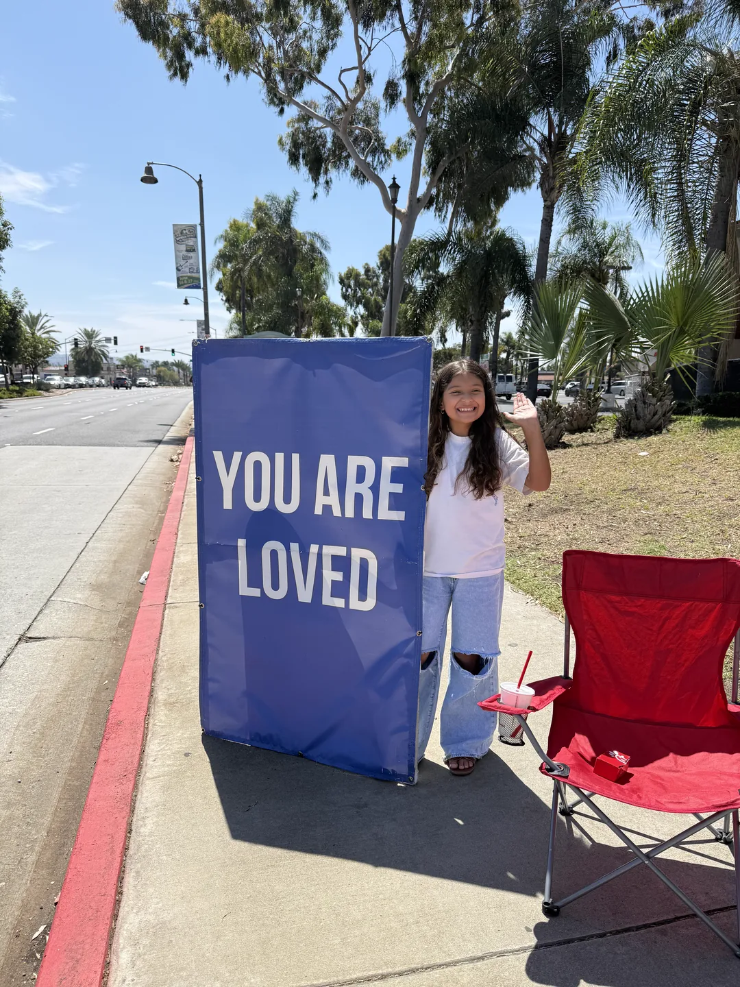 A Sign Ministry volunteer holding a blue We Can't Wait to Meet You sign