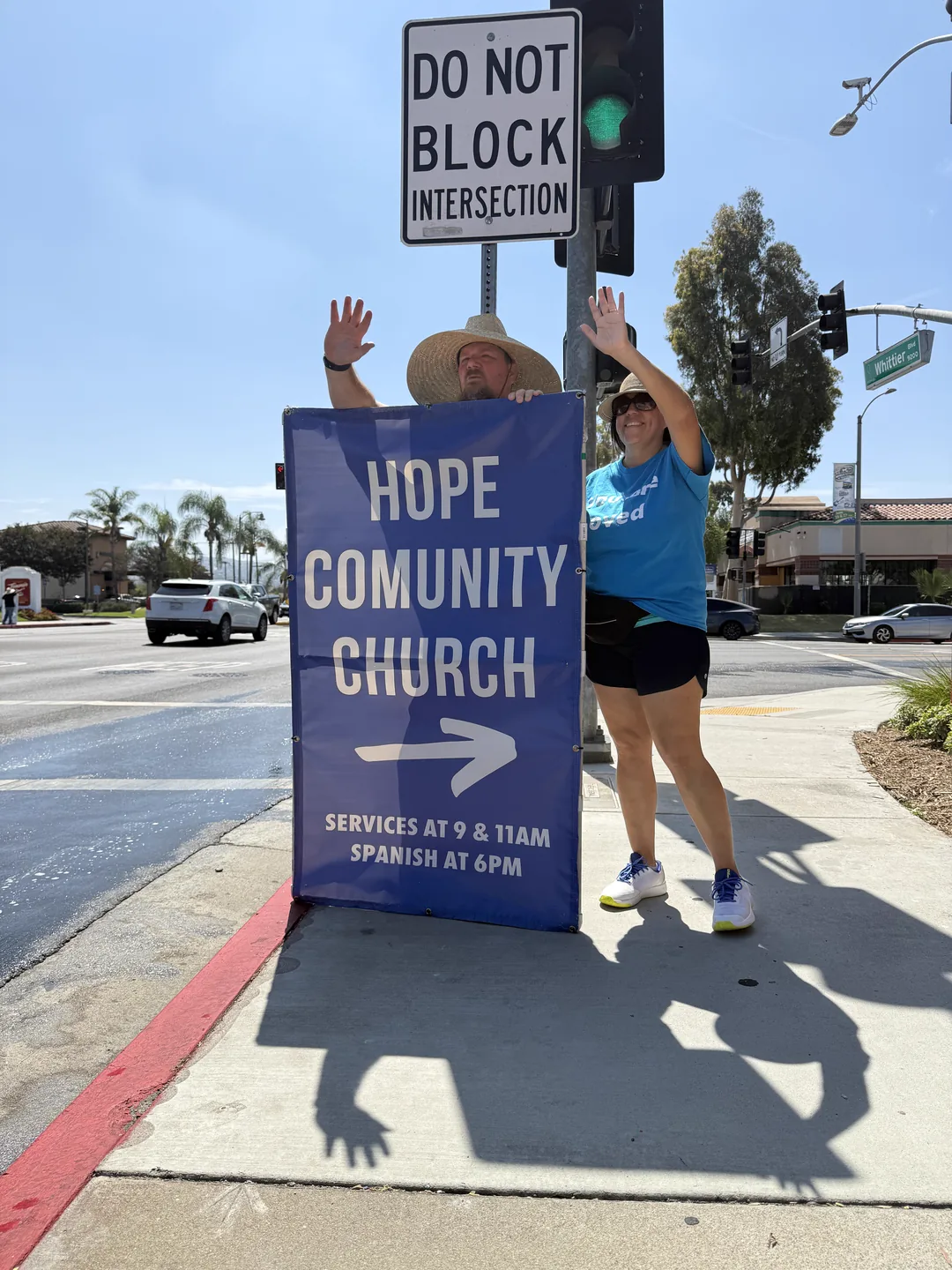 A Sign Ministry volunteer holding a blue You Are Loved sign