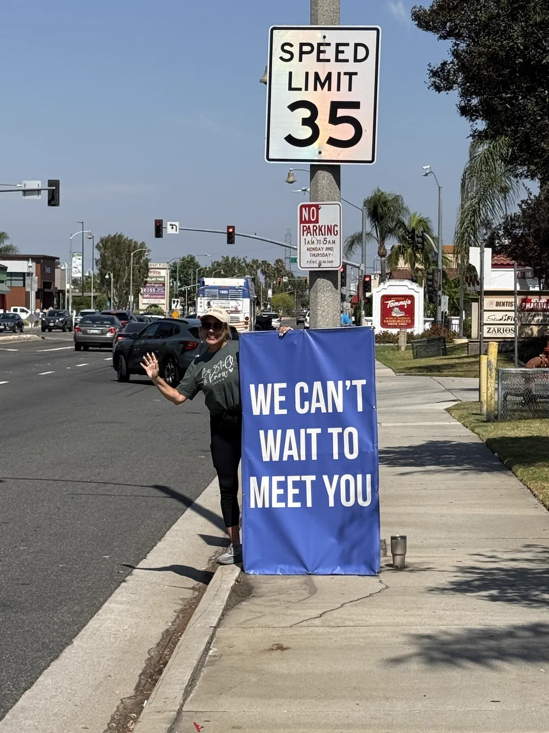 A Sign Ministry volunteer holding a blue Hope Community Church sign