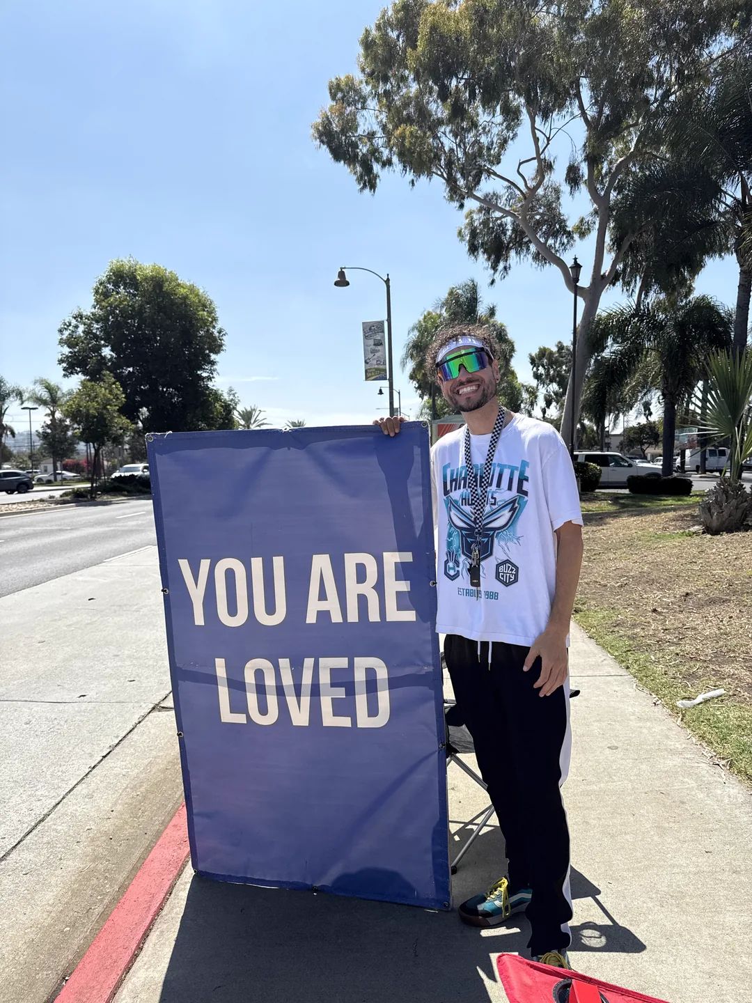 A Sign Ministry volunteer holding a blue You Are Loved sign