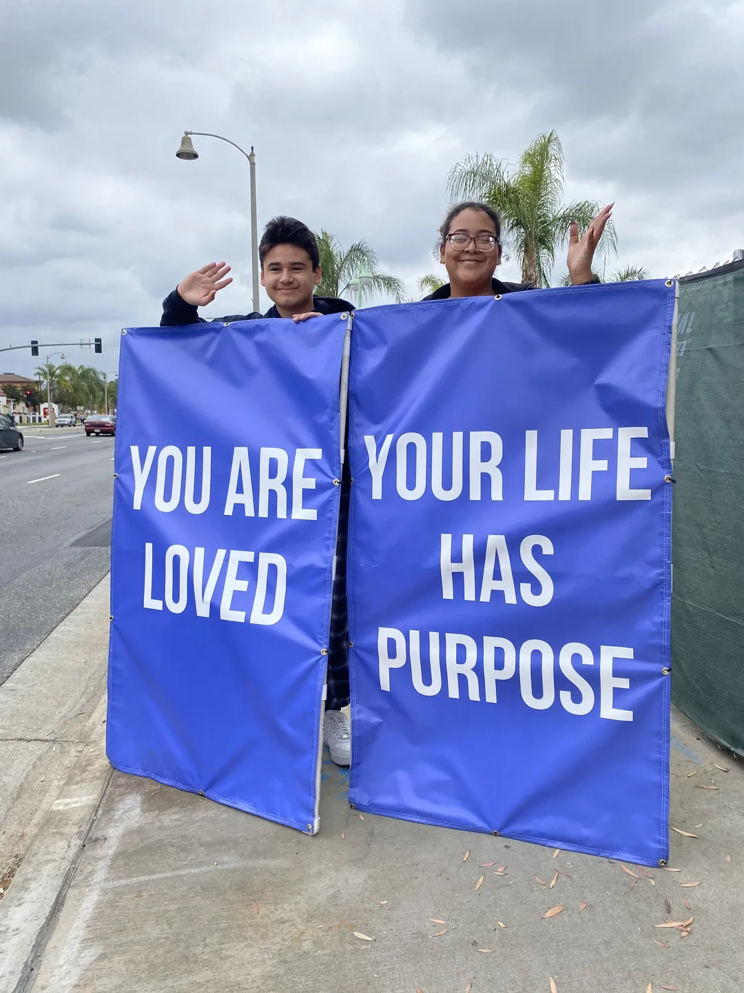 Young people holding blue signs that say You Are Loved and Your Life Has Purpose