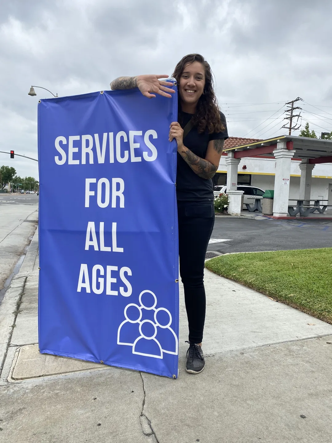A church member holding a blue Services for All Ages sign
